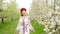 Portrait of pretty ukrainian woman in blossom garden. Girl in traditional embroidery vyshyvanka dress and red wreath