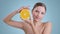 Portrait of pretty woman holding half of orange and smilling while looking to camera. Female model with naked shoulders