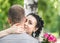 Portrait of pretty young female with small pink roses bouquet smiling, gently hugging male neck and looking into camera at sunny s