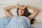 Portrait pretty young girl on bed in modern apartment in the morning. She keeps eyes closed and looks satisfied