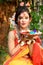 Portrait of pretty young indian girl wearing traditional saree and jewellery, holding powder colours in plate on the festival of