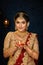 Portrait of a pretty young Indian woman dressed in traditional lehenga, gold jewellery and bangles holding diya in hands on