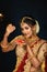 Portrait of a pretty young Indian woman dressed in traditional lehenga, gold jewellery and bangles holding diya in hands on