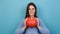 Portrait of pretty young woman holds small ripe orange pumpkin, demonstrates autumn harvest, looking at camera