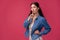 Portrait of a pretty young woman in a light dress and blue shirt standing on pink background in studio. People sincere