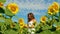 Portrait pretty young woman with long curly cognac hair stands in field with young sunflowers and runs her hand over sunflower