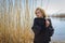 Portrait of a pretty young woman walking outdoors near lake with reed