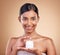 Portrait, product and cream with a model woman in studio on a beige background for beauty or skincare. Face, advertising