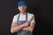 Portrait of a professional butcher in black and white apron, white t shirt and blue baseball hat, armed crossed, knife in his