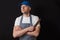 Portrait of a professional butcher in black and white apron, white t shirt and blue baseball hat, armed crossed, knife in his