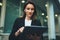Portrait professional female finance lawyer standing near office in evening street communicates online by tablet. Businesswoman