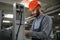 Portrait of Professional Heavy Industry Engineer Worker Wearing Safety Uniform, Hard Hat Smiling. In the Background