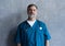 Portrait of professional mature surgeon looking at camera while standing against the grey background.