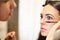 Portrait of professional mua master applying mascara on clients eyelashes