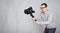 Portrait of professional videographer shooting video using modern dslr camera on 3-axis gimbal over grey concrete wall background