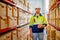 Portrait of professional warehouse worker stand with holding tablet and look at camera in workplace area between shelves with