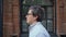 Portrait profile shot of man in eyeglasses and blue shirt walking along the street