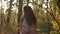 Portrait in profile of young caucasian curly-haired woman walking in sunny autumnal park.