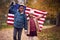 Portrait Of Proud American Boy And Girl Holding Stars And Stripes Flag Outdoors In Autumn