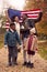 Portrait Of Proud American Family Holding Stars And Stripes Flag Outdoors In Autumn