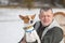 Portrait of proud basenji dog on the hands of mature man while sitting in a wicker chair at winter season