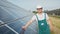 Portrait of proud worker industrial engineer in uniform standing on field with large solar batteries. Ecological farm