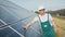 Portrait of proud worker industrial engineer in uniform standing on field with large solar batteries. Ecological farm