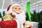 Portrait of a puppet Santa Claus close-up side view. Smiling Christmas santa carrying gifts. Sale christmas tree on background