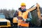 Portrait of a quarry worker standing in front of excavator