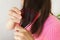 Portrait of a radiant girl combing her dark hair, looking away. The concept of hair care at home