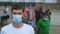 Portrait of rally activist in coronavirus mask among protesting crowd in city.