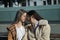 Portrait of real couple of young women, holding hands, sitting on a bench next to each other, putting their foreheads together and