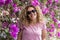 Portrait of real pretty middle age young adult woman smile and pose for the camera with violet flowers background - spring season