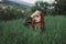 Portrait of a red-haired girl dressed in an ethnic dress. Green grass. Mountain. Merging with nature