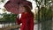 Portrait of a red head beautiful woman walk under rain with umbrella. Pretty, happy woman wearing red coat with umbrella