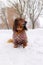 Portrait of Red longhaired dachshund sitting on snow in winter park, little fluffy doggy wearing winter clothin