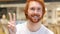 Portrait of Redhead Beard Man Gesturing Victory Sign in Cafe