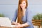 Portrait redhead woman with laptop on terrace