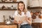 Portrait of relaxed blond woman reading book while standing in stylish wooden kitchen at home