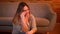 Portrait of relaxed plus size long-haired model sitting on floor having a voicecall on smartphone in cozy home