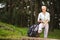 Portrait of Relaxing Senior Woman Posing with Smartphone and Tourist Backpack in Forest Outdoors
