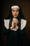 Portrait of religious nun praying with eyes closed holding crucifix rosary