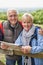 Portrait Of Retired Couple On Walking Holiday Resting On Gate With Map