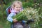 Portrait of riding on bicycle child seat little blonde girl with bouquet of wild chamomiles in hands