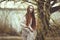 Portrait of a romantic girl with red hair in the wind under a willow tree.