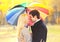 Portrait romantic kissing couple in love with colorful umbrella together at warm sunny day over yellow leafs