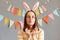 Portrait of romantic pretty woman wearing rabbit ears holding colorful Easter cake pops isolated on gray decorated background,