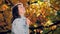 Portrait of romantic woman in park, autumn wind and leaf fall