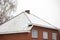 A portrait of a roof of a house with a little bit of white snow on it. The chimney of the building is already clear of snow