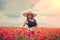 portrait of rpetty ukrainian woman in black top and hat with big bouquet of poppies in field